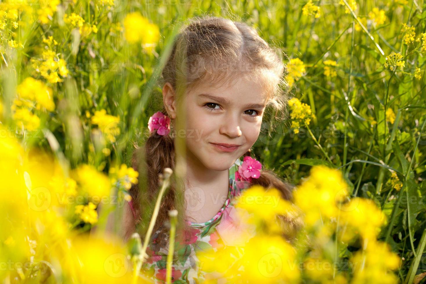 niña sentada en la hierba y flores foto