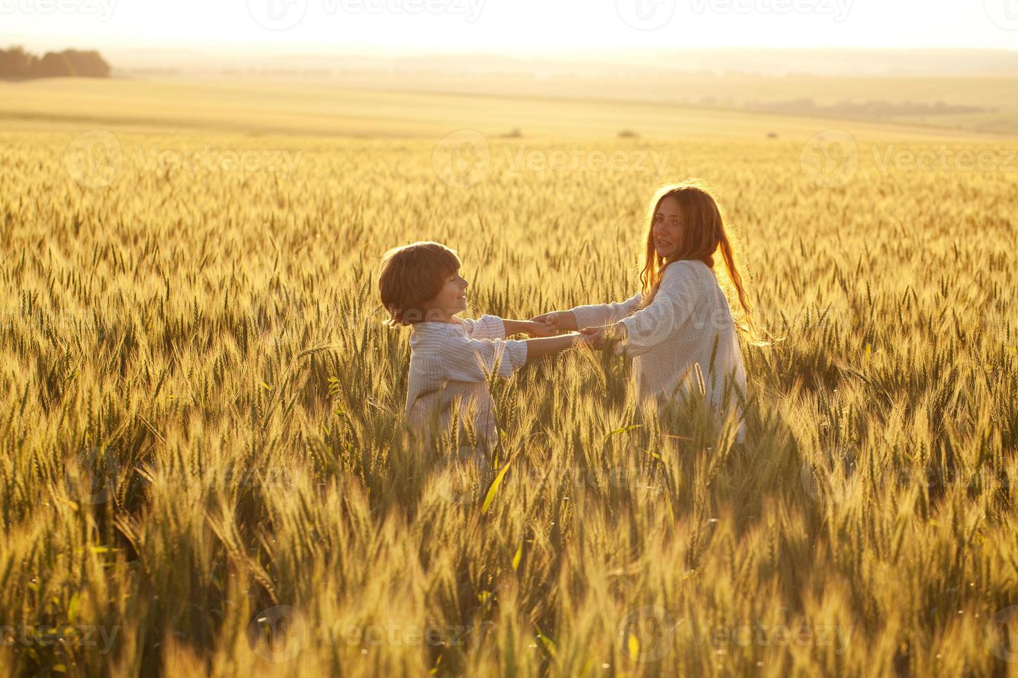 Happy mother and son are running through a wheat field photo