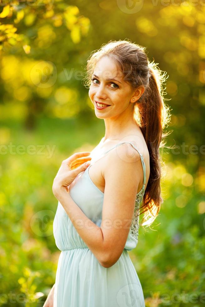 Happy young woman in dress in summer garden photo