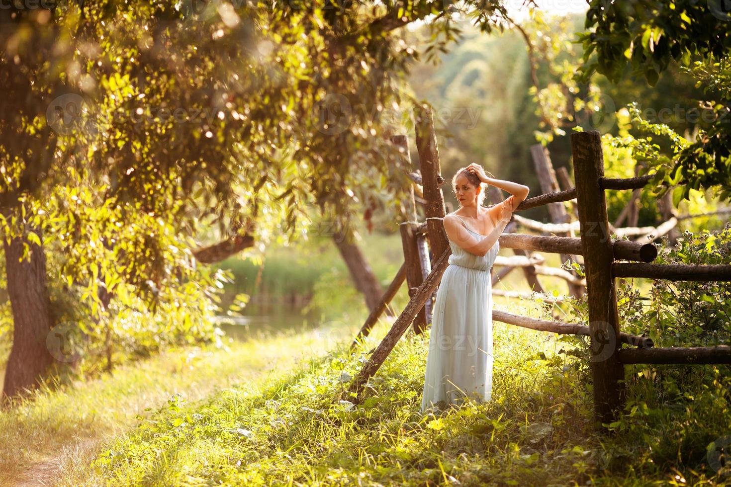 Woman stands near a hedge on a summer evening photo