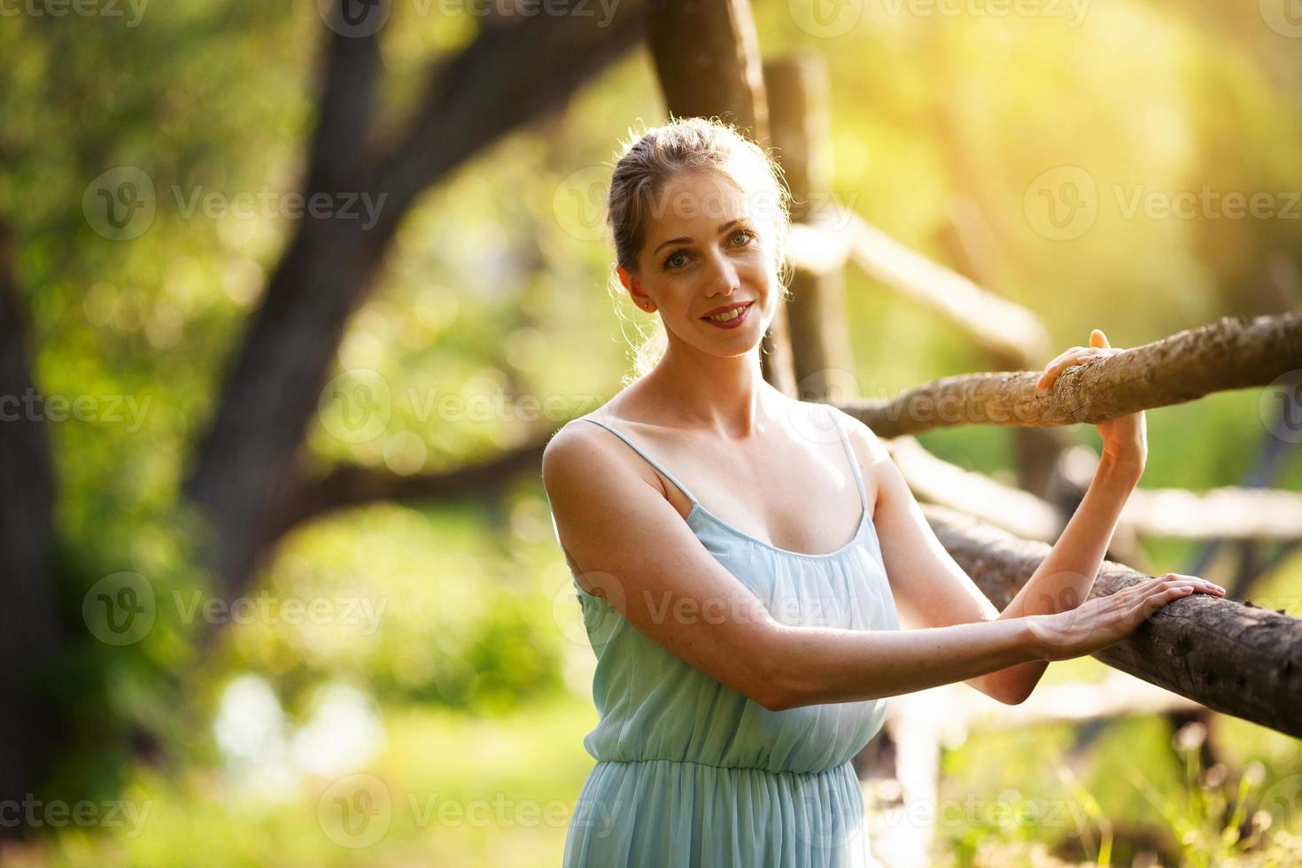 Mujer bonita joven se encuentra cerca del seto en el jardín foto