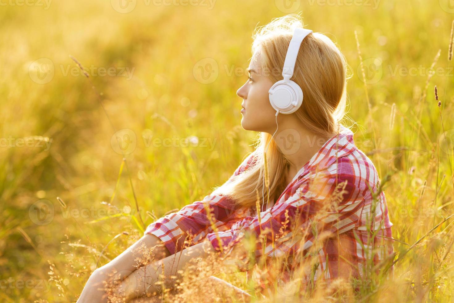 chica con auriculares sentada en la hierba foto