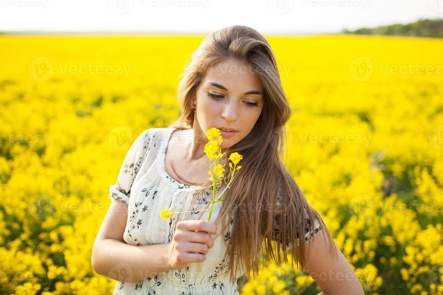 niña bonita que huele flores silvestres amarillas foto