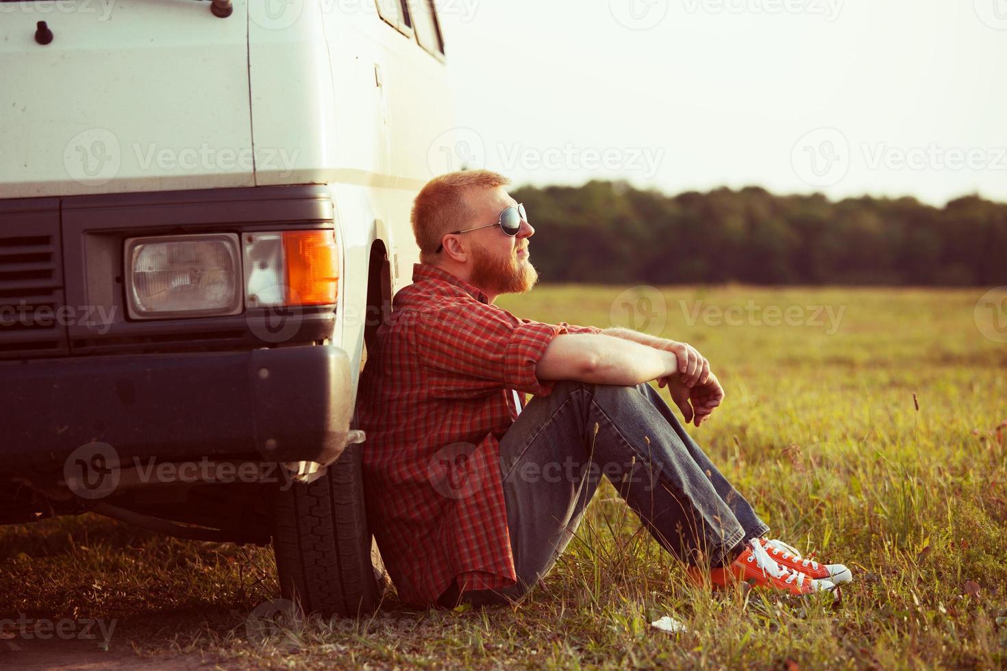 Driver sits next to his car photo