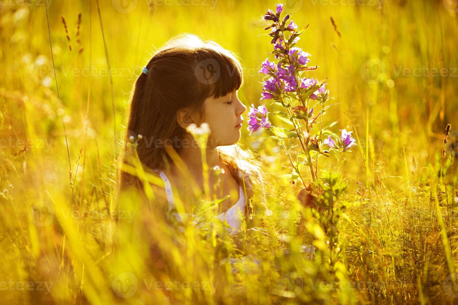 niña feliz oliendo una flor foto