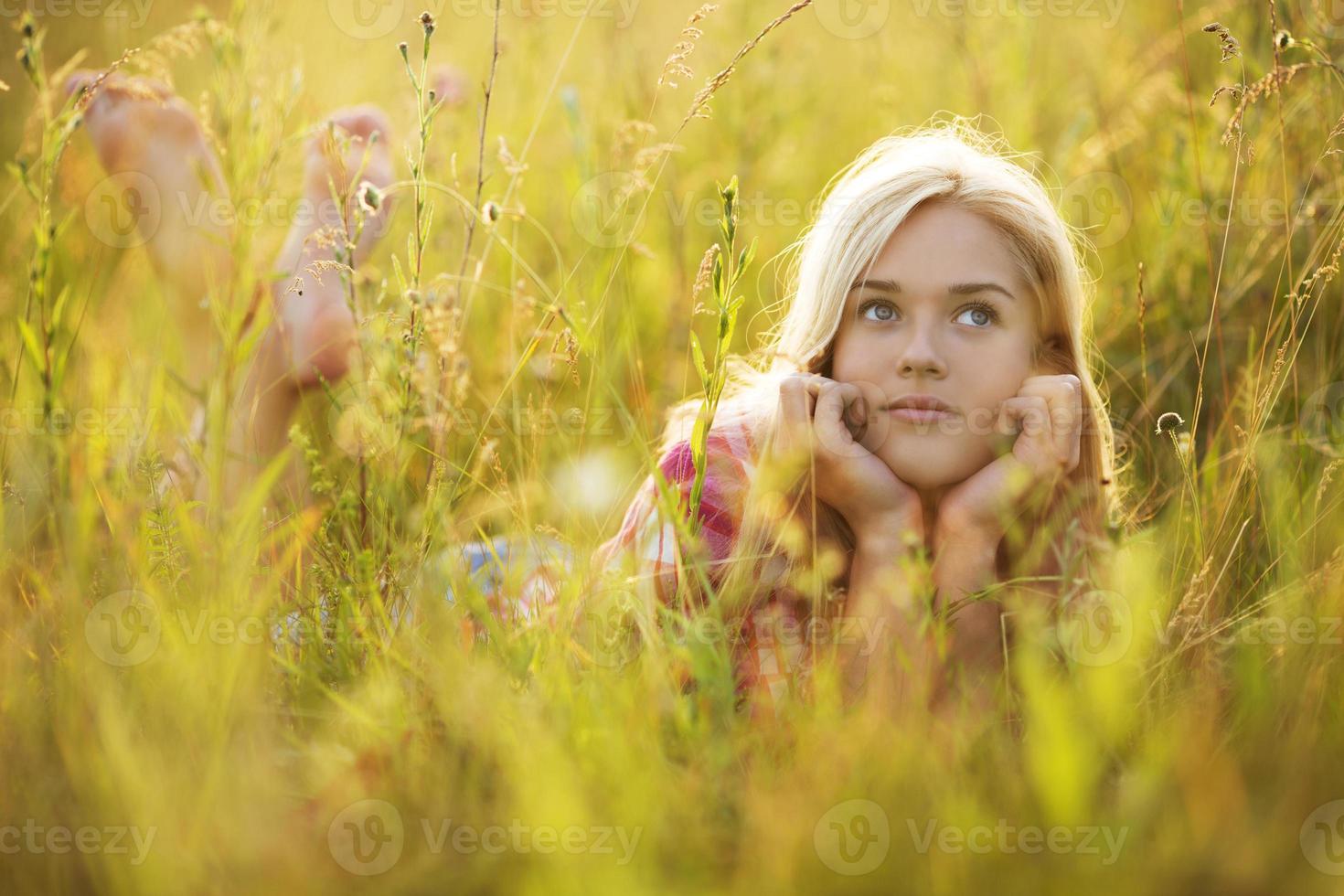 niña feliz en la hierba mirando hacia arriba foto