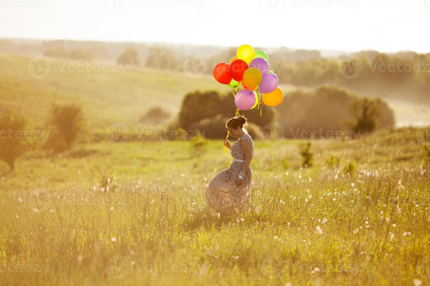 Happy young woman with balloons among a field photo