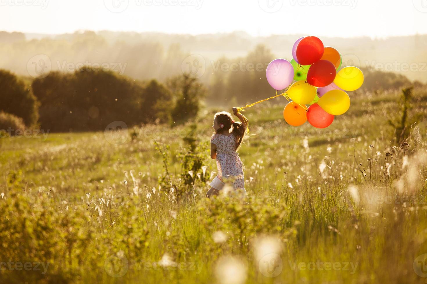 niña corre por el campo con pelotas inflables foto