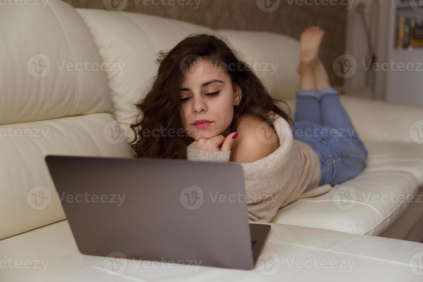 mujer está acostada en el sofá con laptop foto