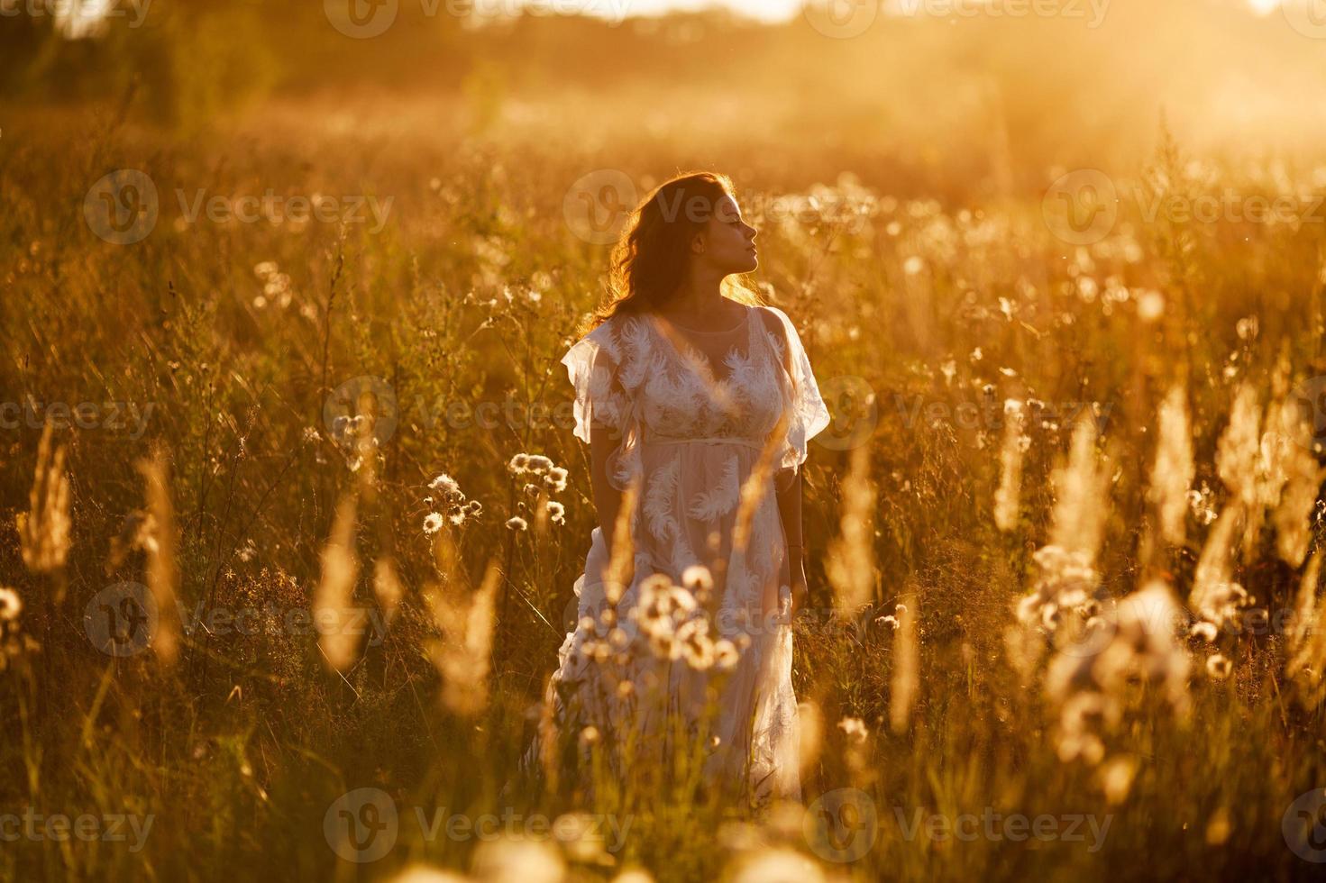 niña está de pie en el campo al atardecer foto