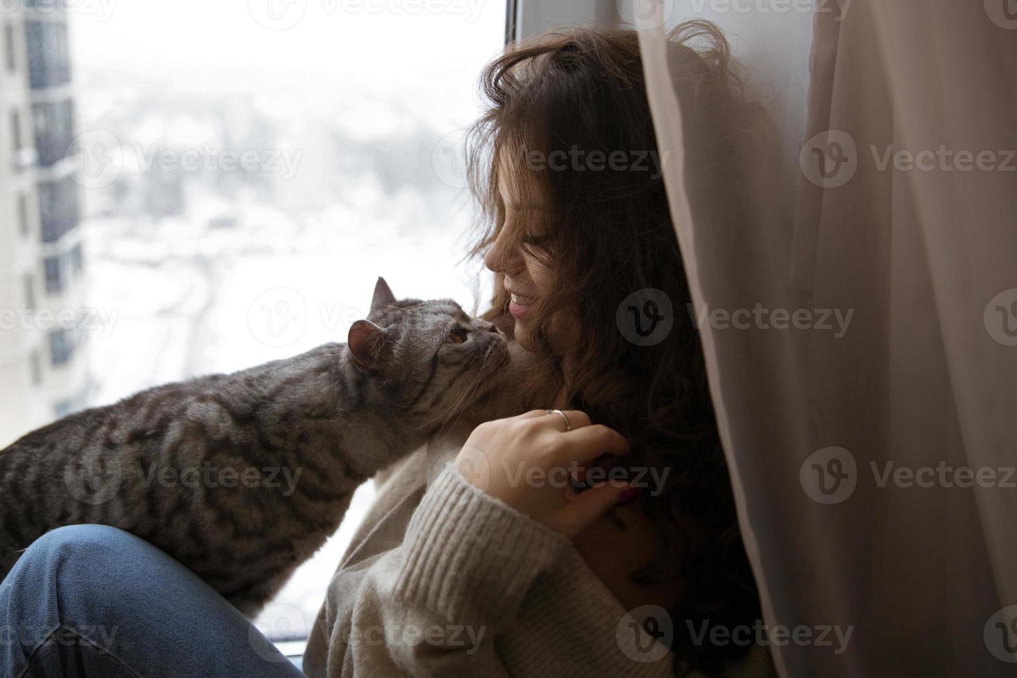 niña sentada y acariciada con un gato foto