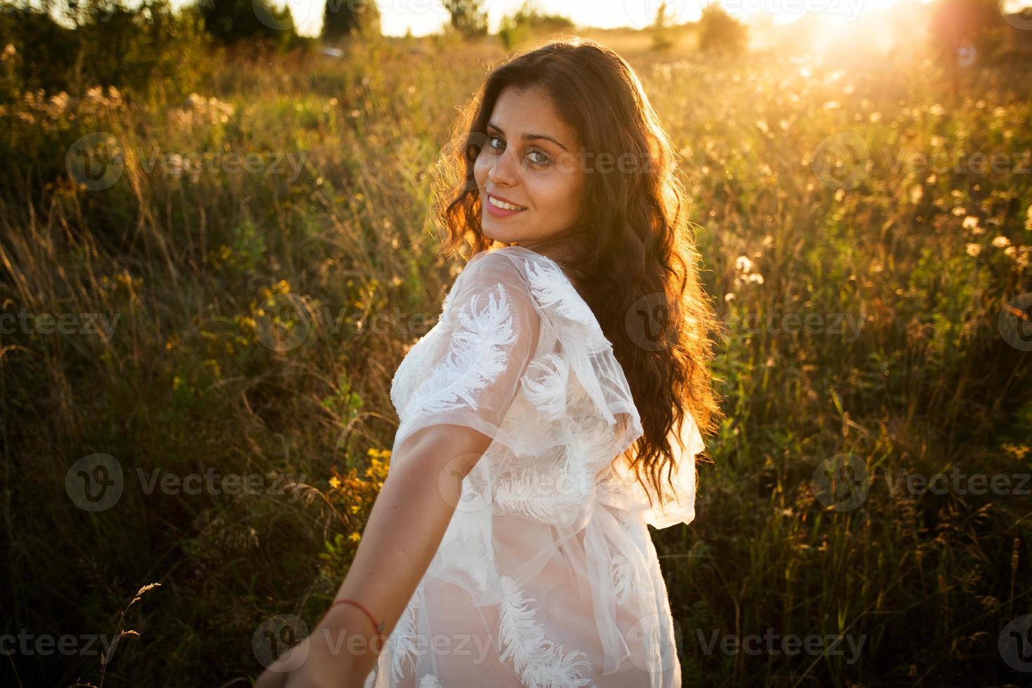 niña en un vestido camina en el campo al atardecer foto