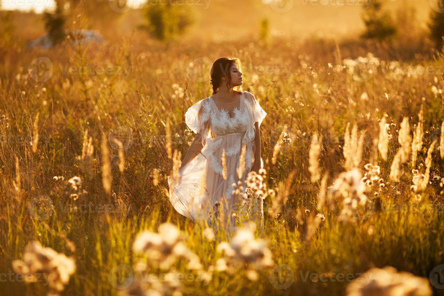 niña camina por un prado al atardecer foto