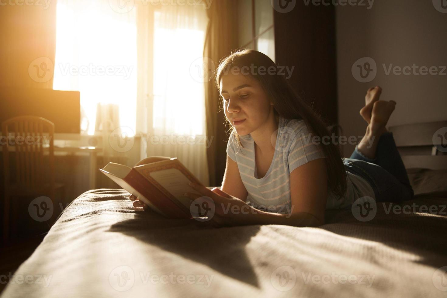 Cute girl lies and reads a book photo