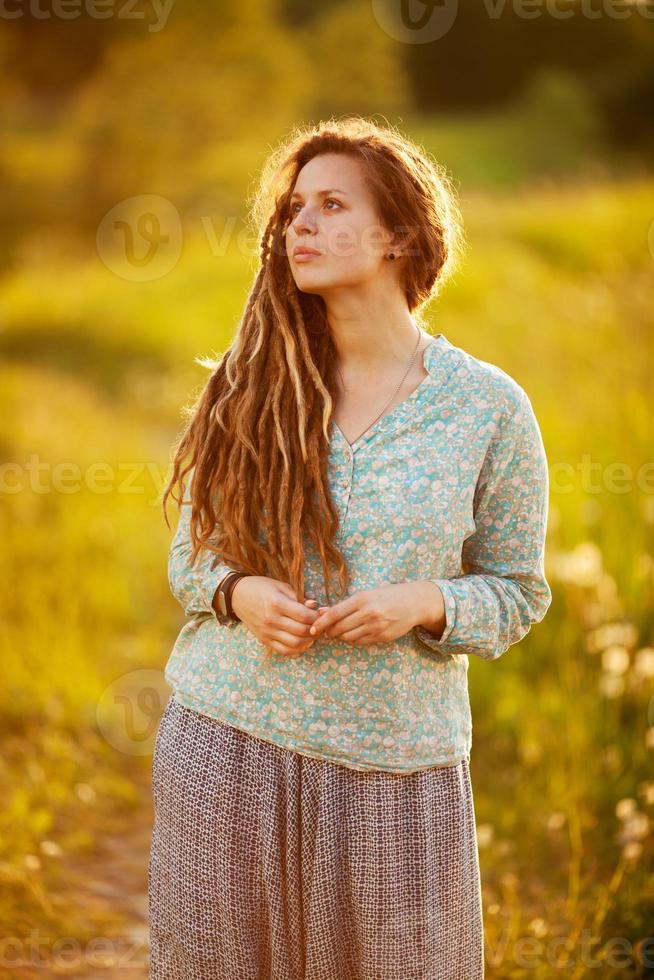 Girl with dreadlocks is standing and dreaming photo