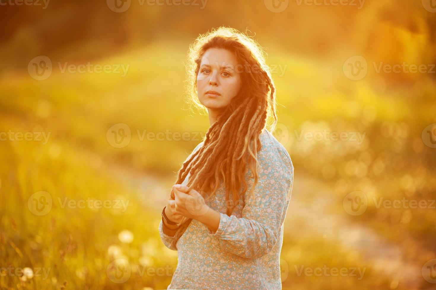 Girl with dreadlocks standing in the middle of the meadow photo