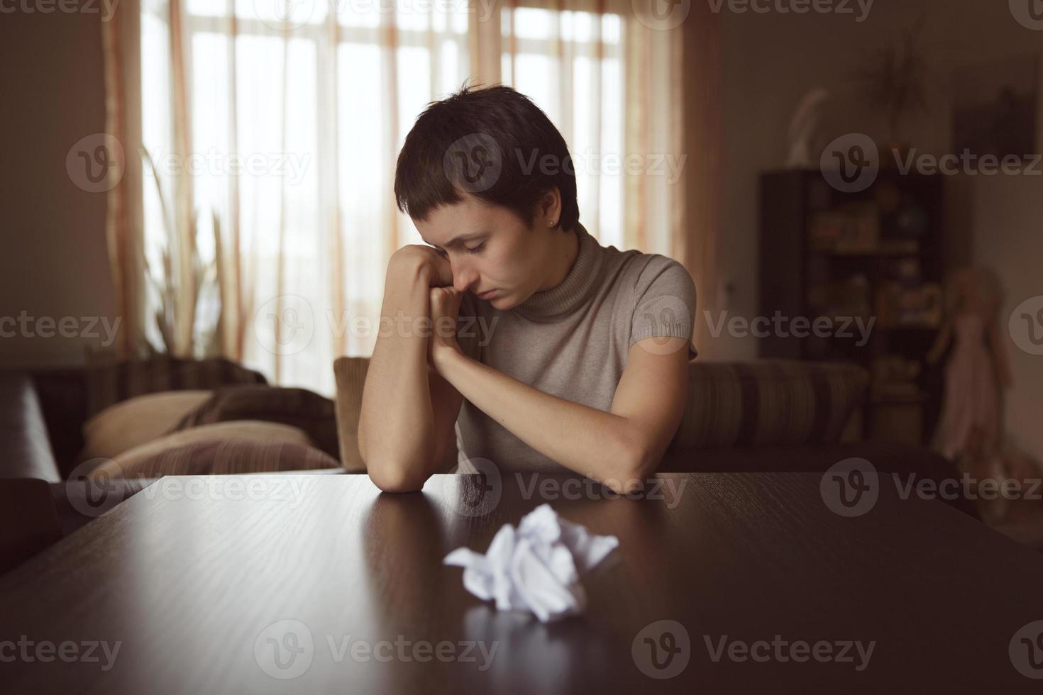 Very sad woman sits in front of crumpled letter photo