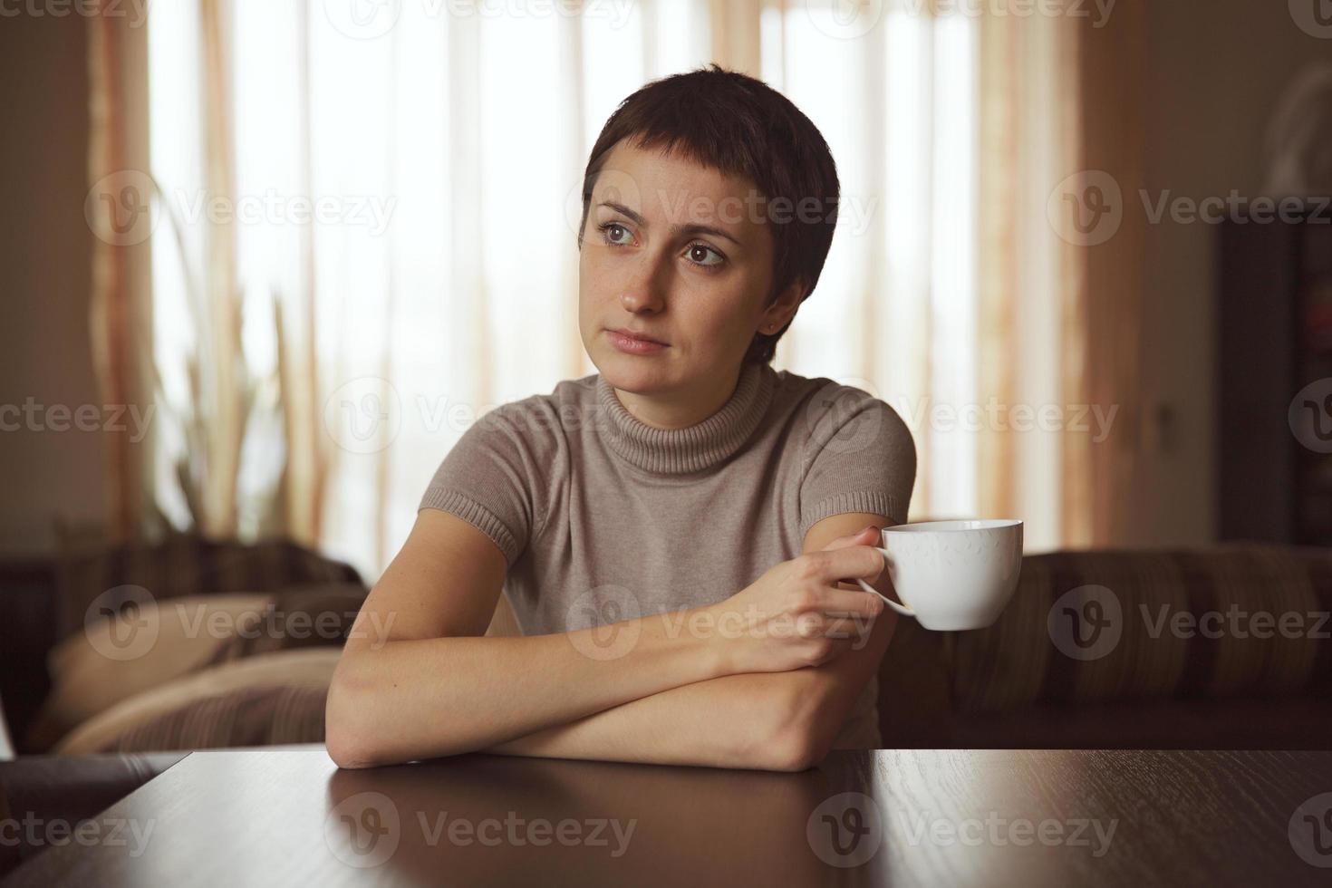 niña pensativa sentada con una taza de café foto