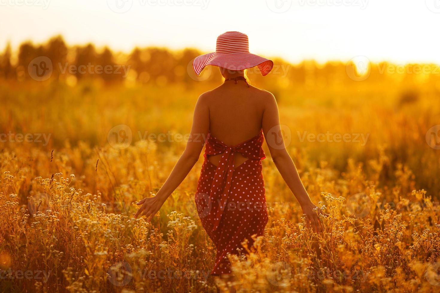 Woman in a hat walking through fields of flowers photo