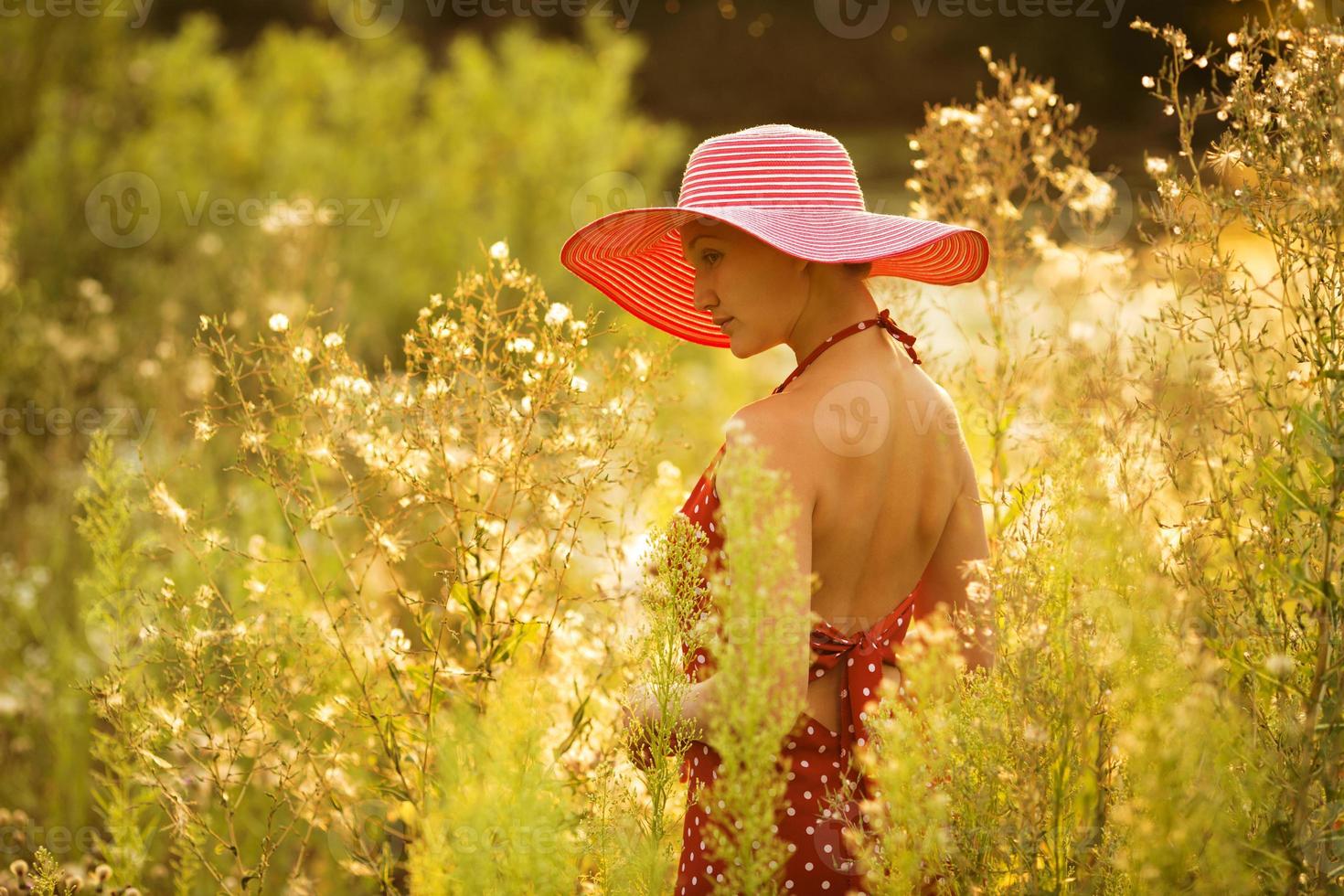 hermosa mujer camina entre altas flores silvestres foto