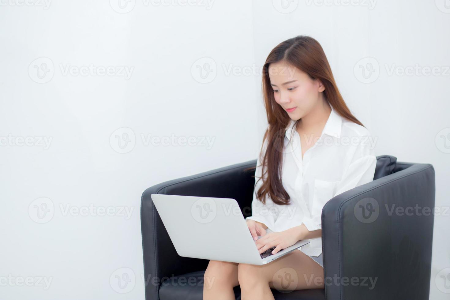 mujer asiática joven que usa la computadora portátil para el ocio en el sofá. foto