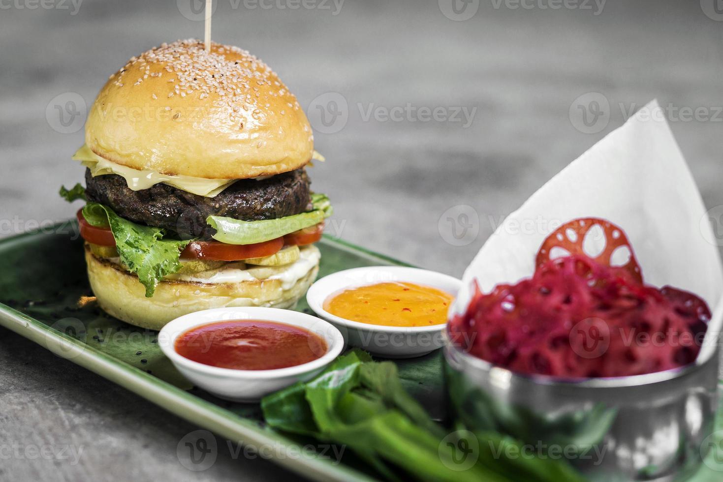 Modern fusion beef burger set with lotus chips ketchup and spicy chili sauces photo