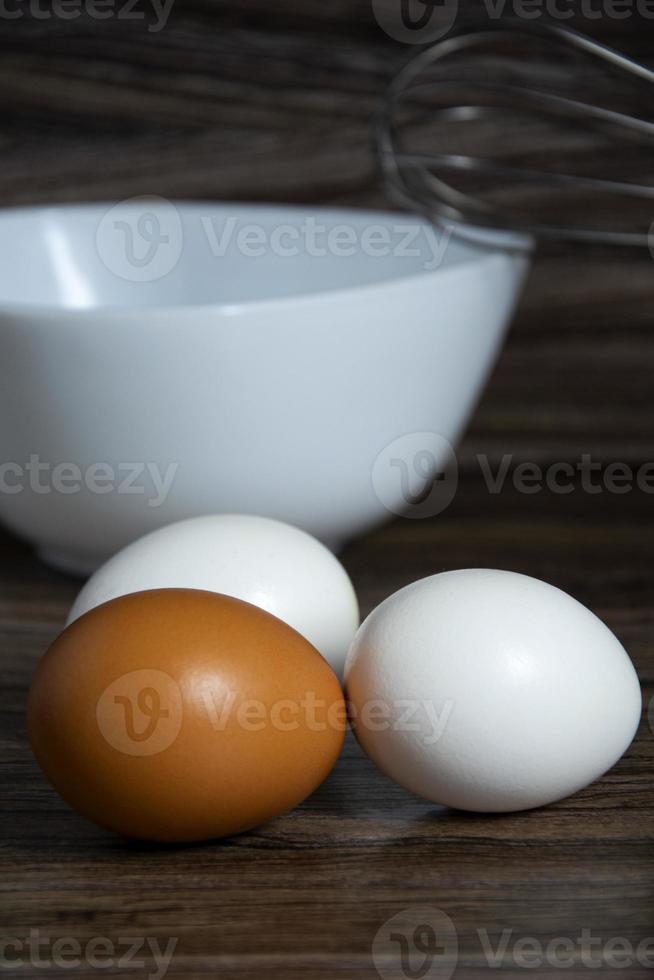 Eggs close up. White and orange eggs lie on the table near the bowl. photo