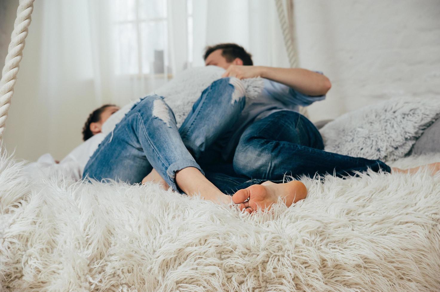 una pareja joven en jeans en una cama colgada foto