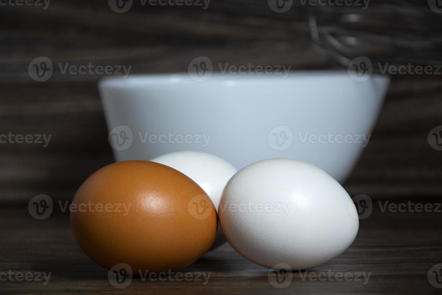 Eggs close up. White and orange eggs lie on the table near the bowl. photo