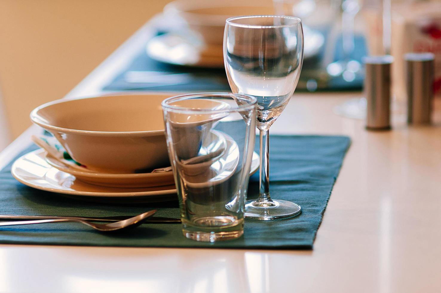 Close up dining setup with empty wine and water glasses, silver cutlery and blue napkins, decorations and items served for food, arranged by catering service in a modern restaurant, cafe photo