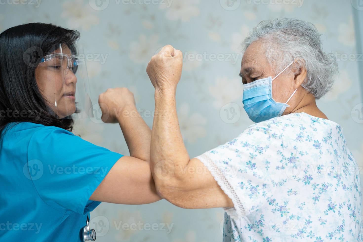 Asian doctor and elder patient bump elbows to social distancing photo