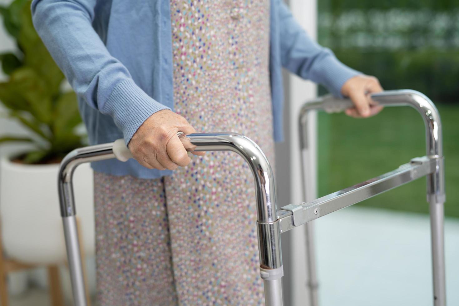 Paciente mujer mayor asiática caminar con andador en el hospital foto