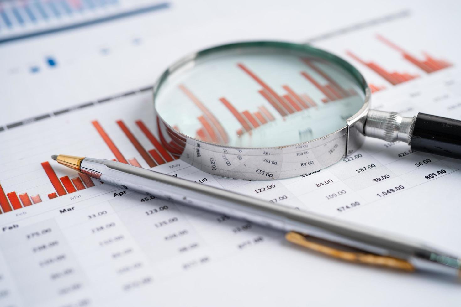 Magnifying glass on charts graphs paper. Financial development photo