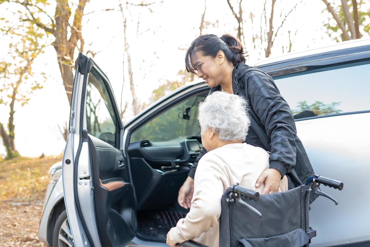 Help and support asian senior woman patient  get to her car, photo