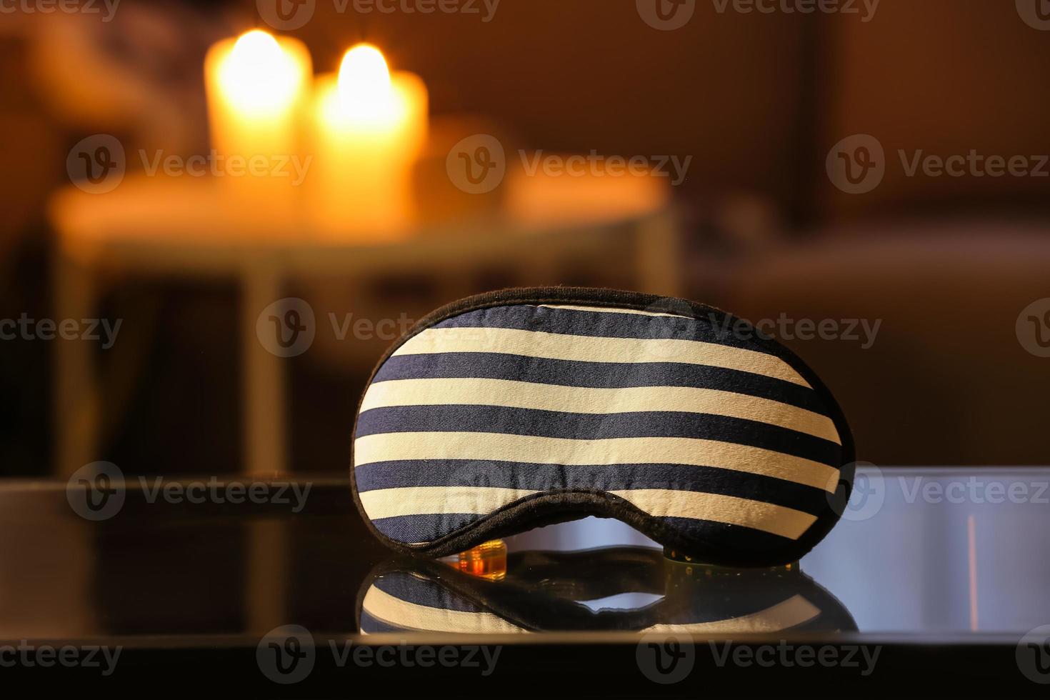 Stylish sleeping mask on table in dark room photo