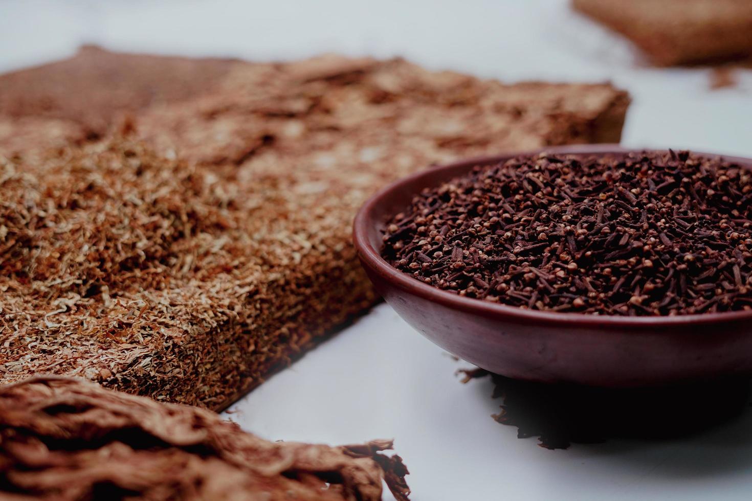 Dried sliced tobacco leaf and cloves inside bowl photo