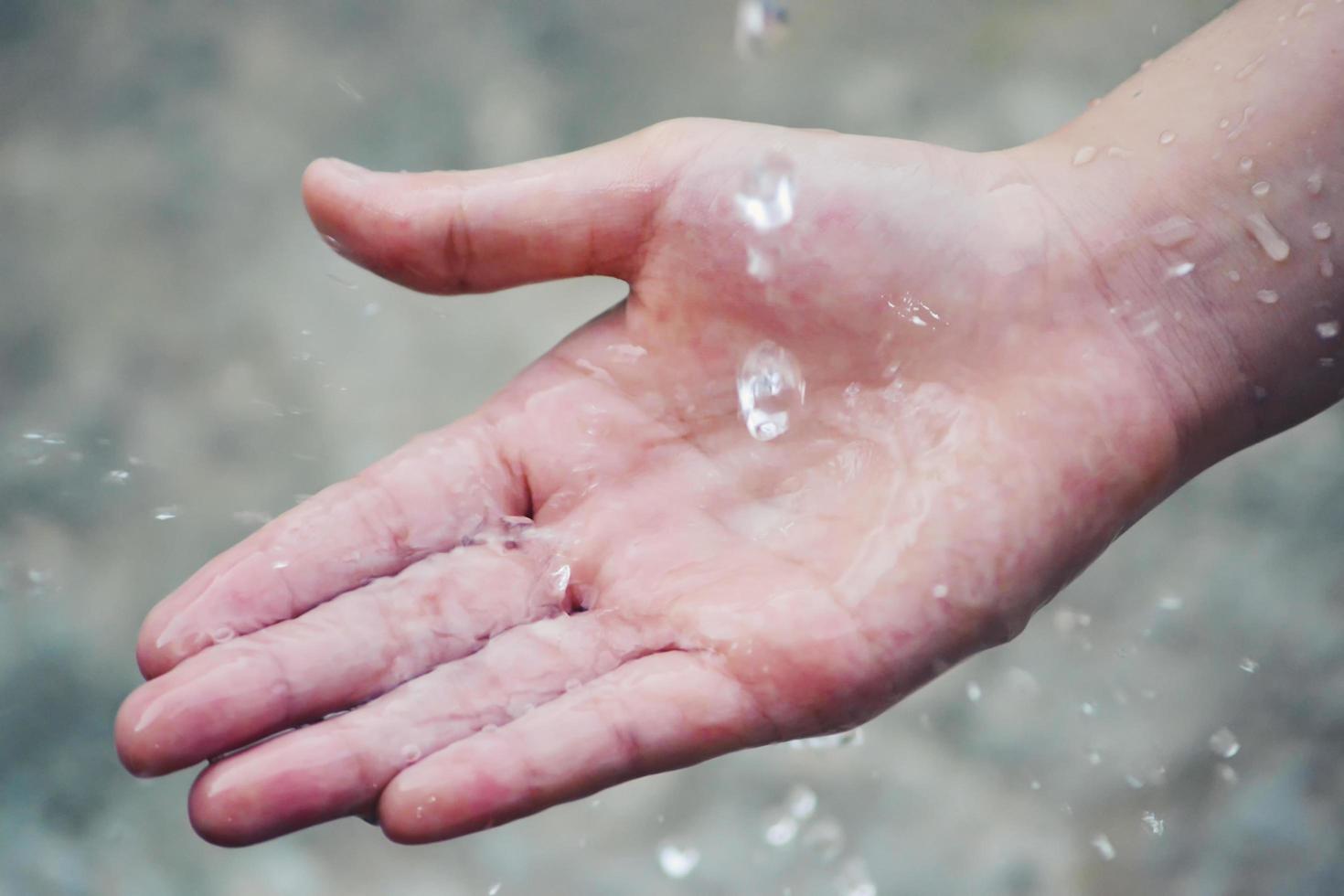 Hand catches water drops coming out of faucet photo