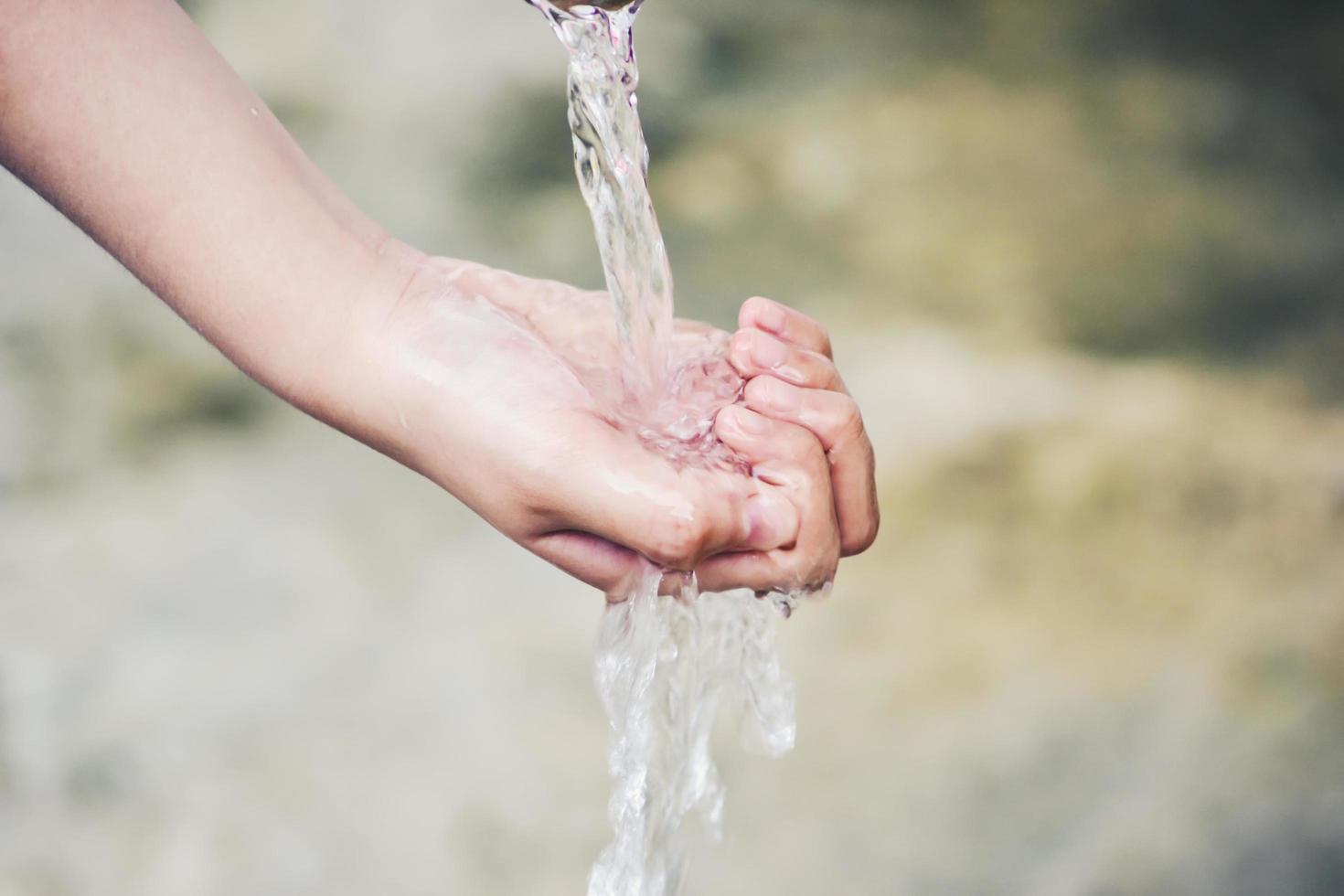 Hand catches water drops coming out of faucet photo