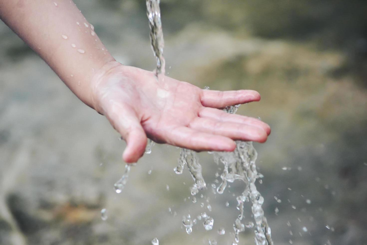 Hand catches water drops coming out of faucet photo