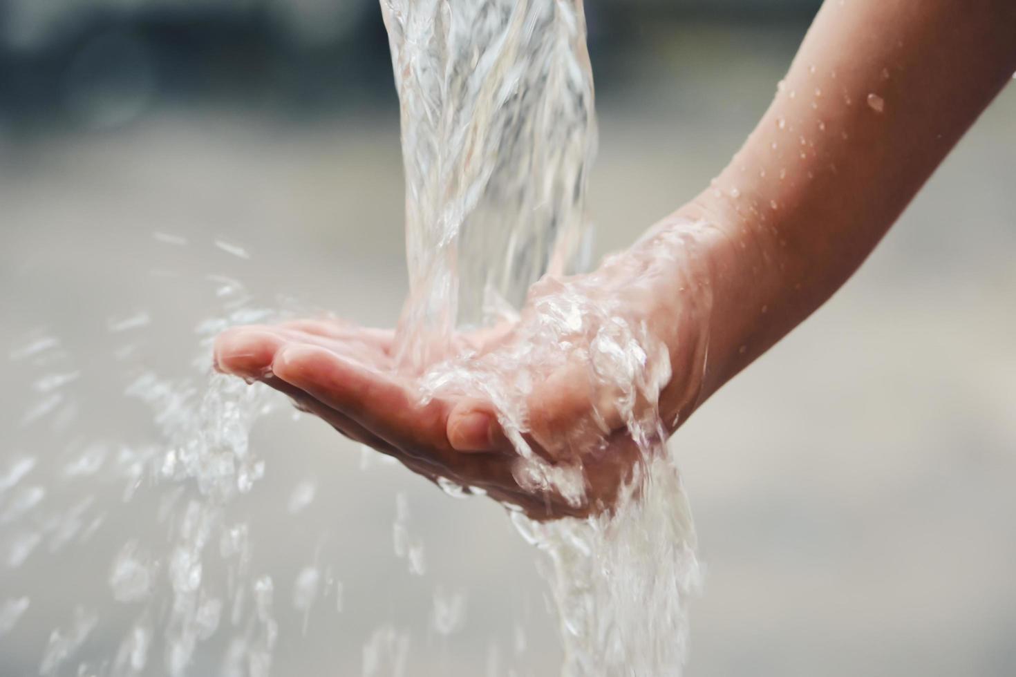 Hand catches water drops coming out of faucet photo