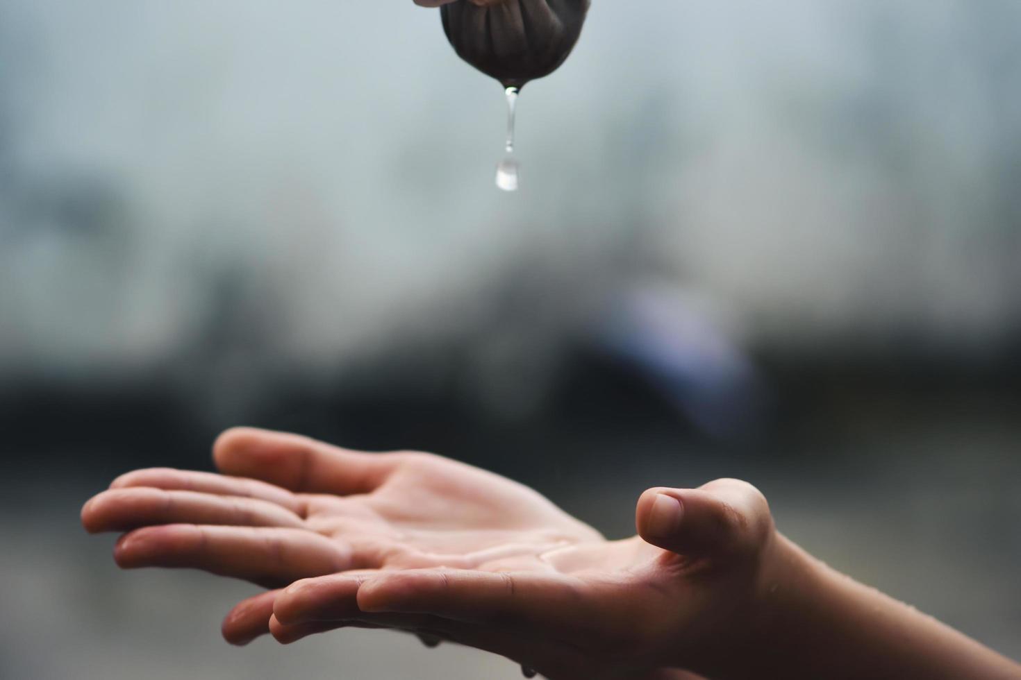 Hand catches water drops coming out of faucet photo