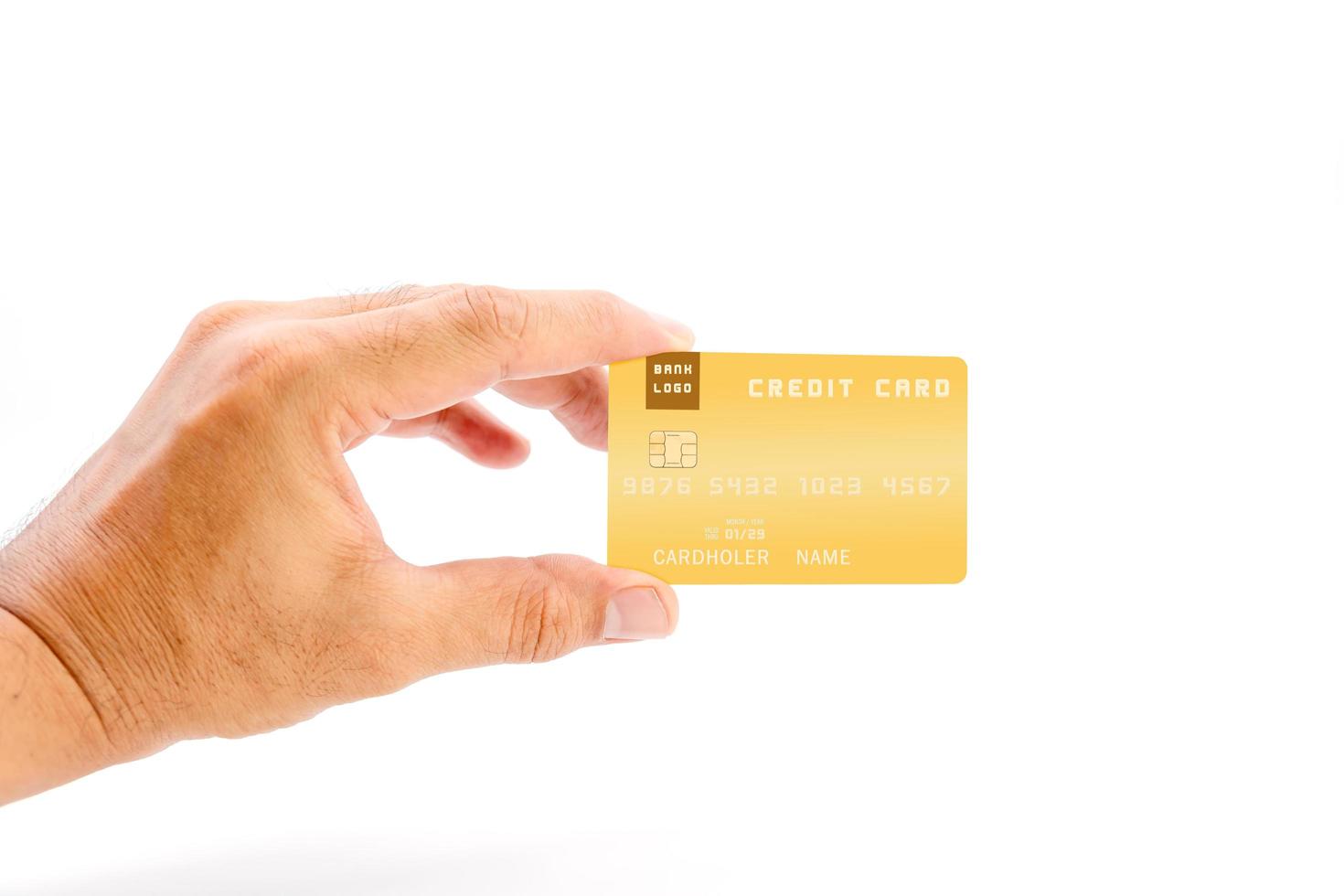 Mano humana sosteniendo una tarjeta de crédito bancaria de color amarillo sobre fondo blanco. foto