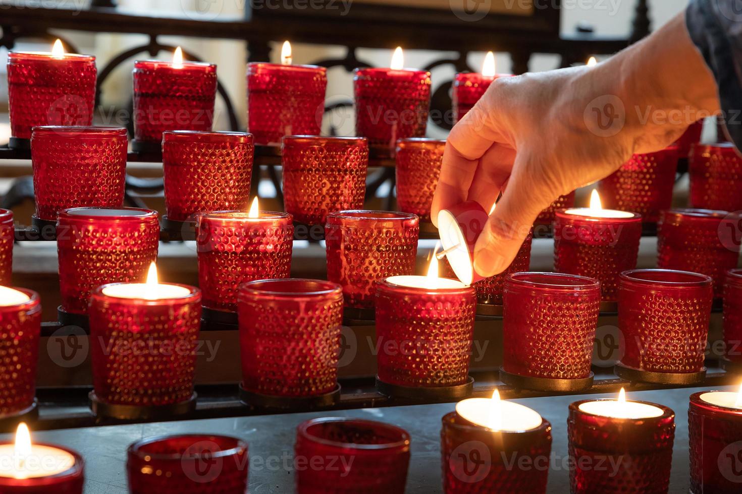 Lighting a red sacrificial candle in a Christian church photo