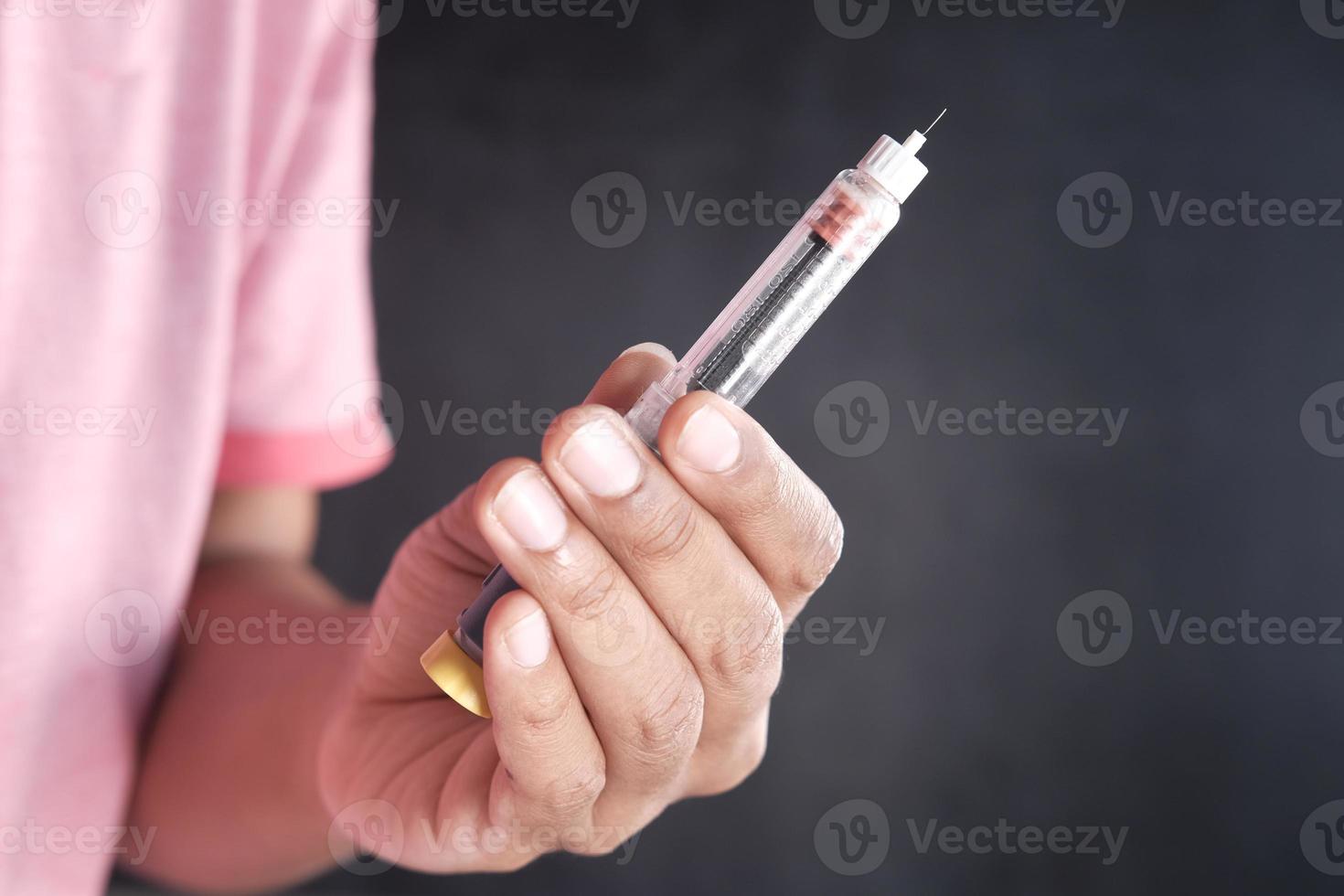 Hand hold Insulin pens against black background photo