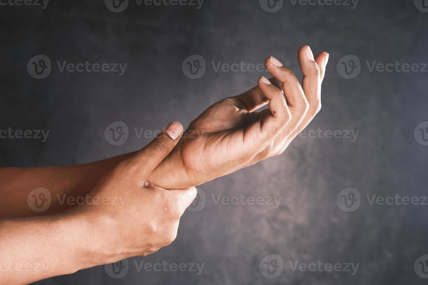 Hombre que sufre dolor en la mano contra el fondo negro foto