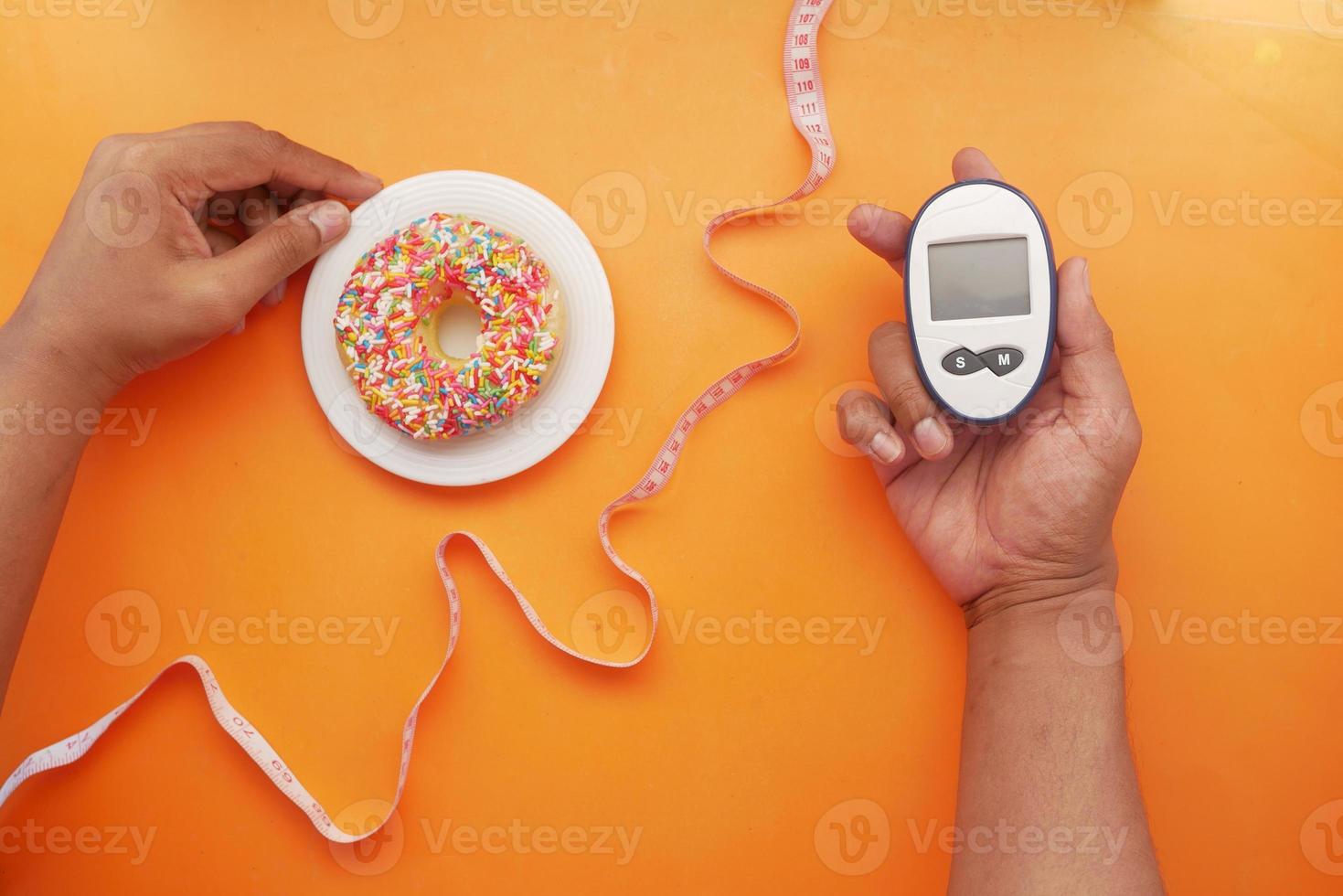 Mantenga a mano herramientas de medición para diabéticos y donas en naranja foto