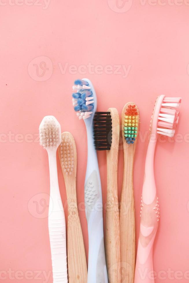 Colorful toothbrushes on pink background photo