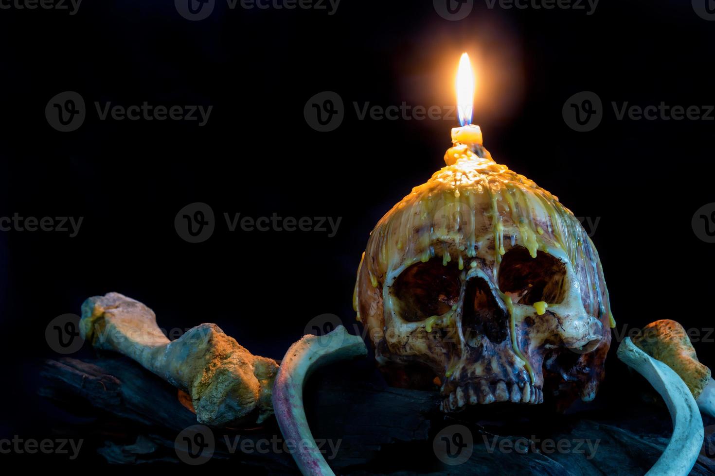 skull with candle light on top and bone on grunge wood photo