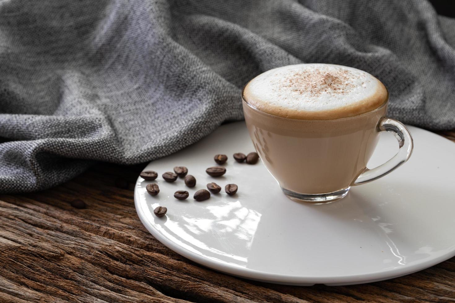 Taza de café capuchino transparente sobre fondo de madera foto