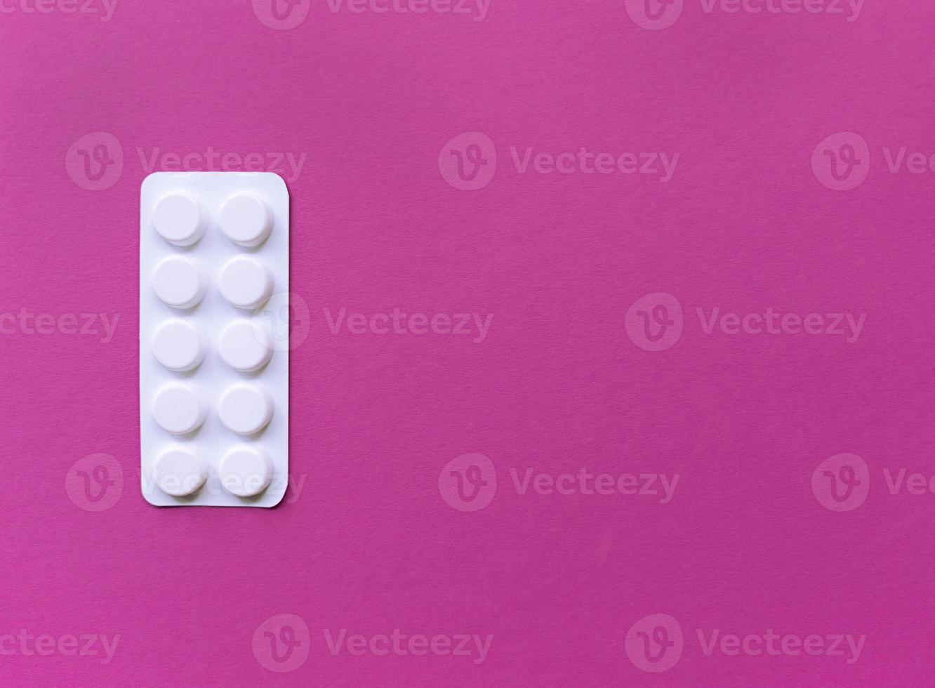 Blister de pastillas blancas sobre fondo de color rosa con espacio de copia foto